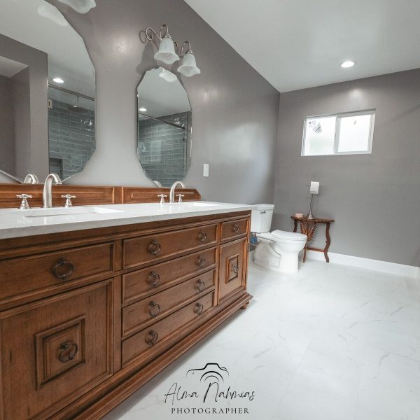 Bathroom with a large wooden double vanity, two mirrors, and a glass shower.