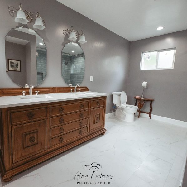 Bathroom with double vanity, two mirrors, and a toilet.