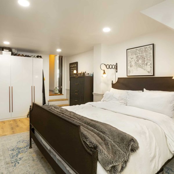 Bedroom with a bed, white wardrobes, and a chest of drawers.
