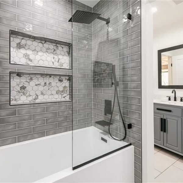 Modern bathroom with gray subway tiles, white tub, and gray vanity.