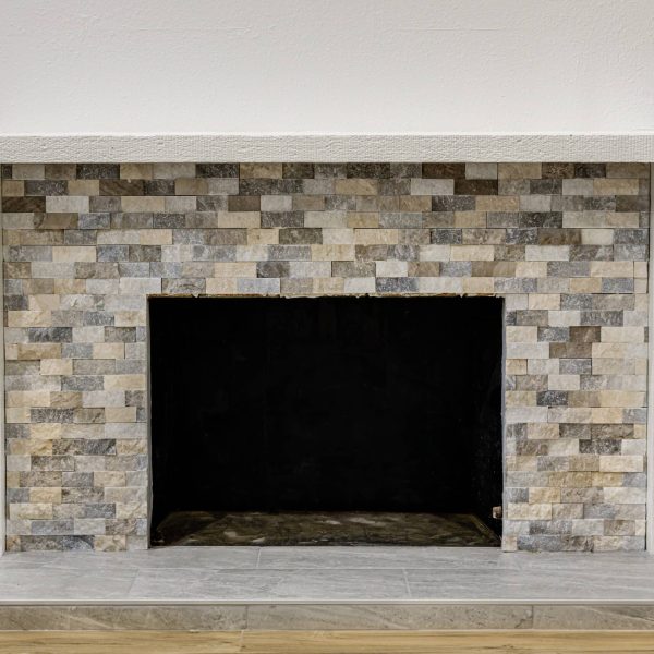 A fireplace with a black firebox and a stone tile surround.