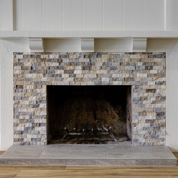 A fireplace with a stone tile surround and a white mantelpiece.