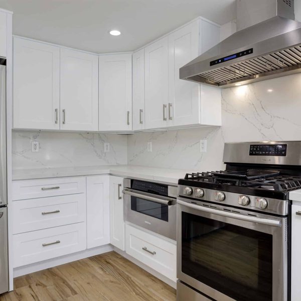 Modern kitchen with white cabinets, stainless steel appliances, and marble countertops.