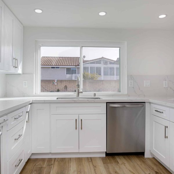 Modern white kitchen with stainless steel appliances and a window