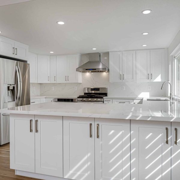 Modern white kitchen with stainless steel appliances and marble countertops.