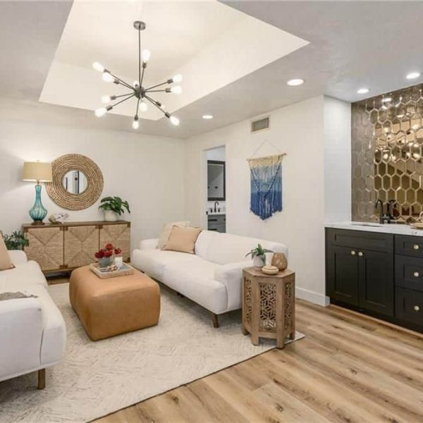 Modern living room with white sofas, a bar, and a unique chandelier.