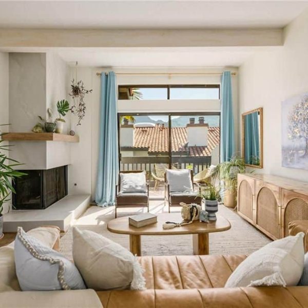 Living room with fireplace, brown leather sofa, and outdoor view.
