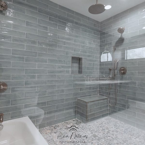 Modern bathroom with blue subway tiles, glass shower, and white tub